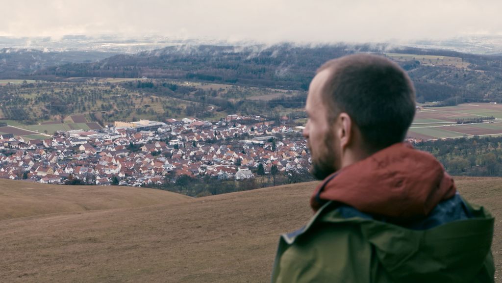 Mann schaut über eine Mittelgebirgs-Landschaft