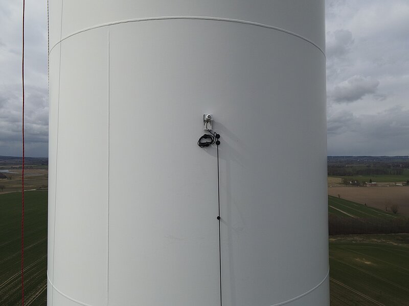 Blick auf das obere Turmsegment einer Windenergieanlage mit dem neu installieren Mikrofon