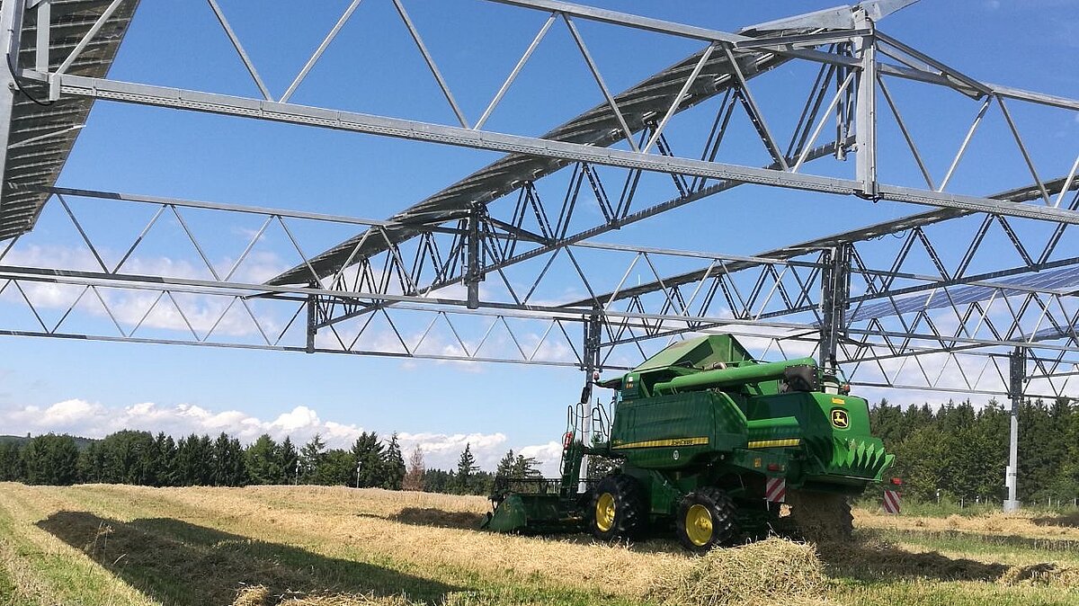 Agricultural utility vehicle cultivates a field under a PV elevation