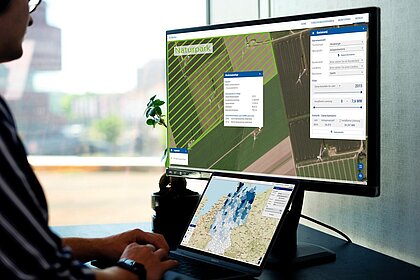 A man sits in front of a screen showing different aerial photos and maps