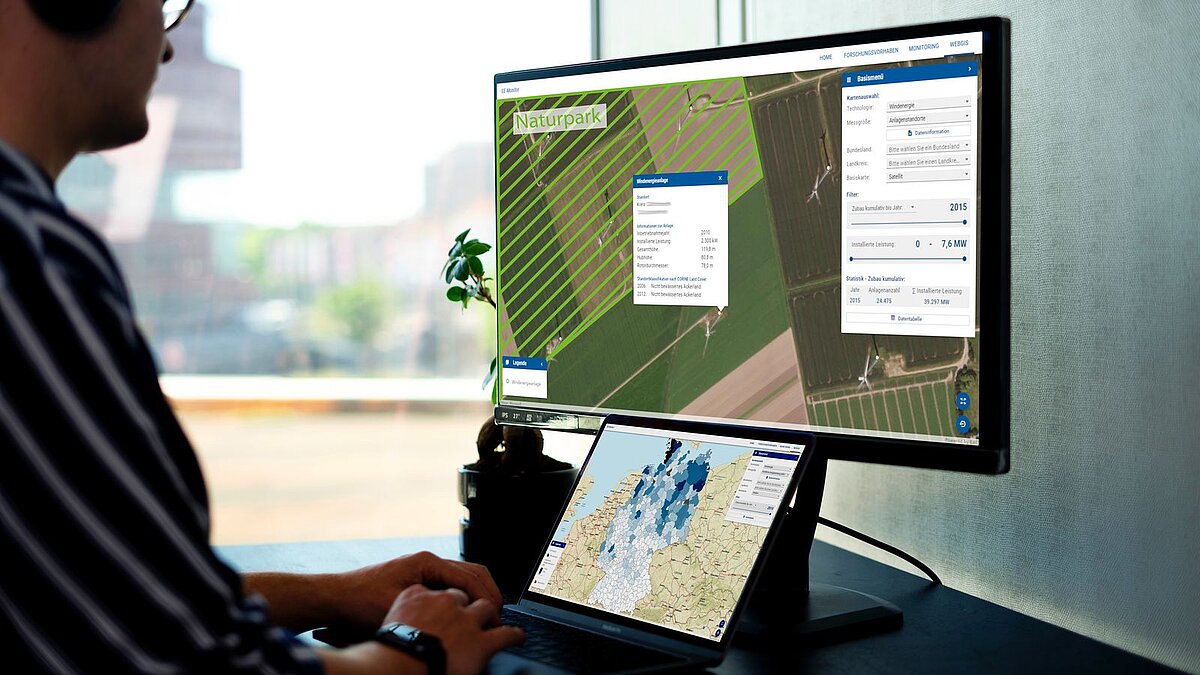A man sits in front of a screen showing different aerial photos and maps