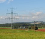 An overhead power line in a green landscape
