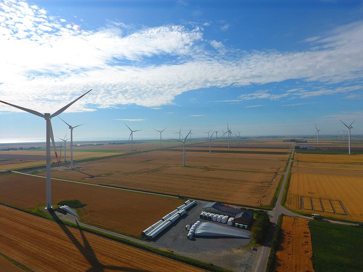 Luftbild eines Windparks, auf dem Boden sind Rotorblätter und weitere Bauteile zu erkennen